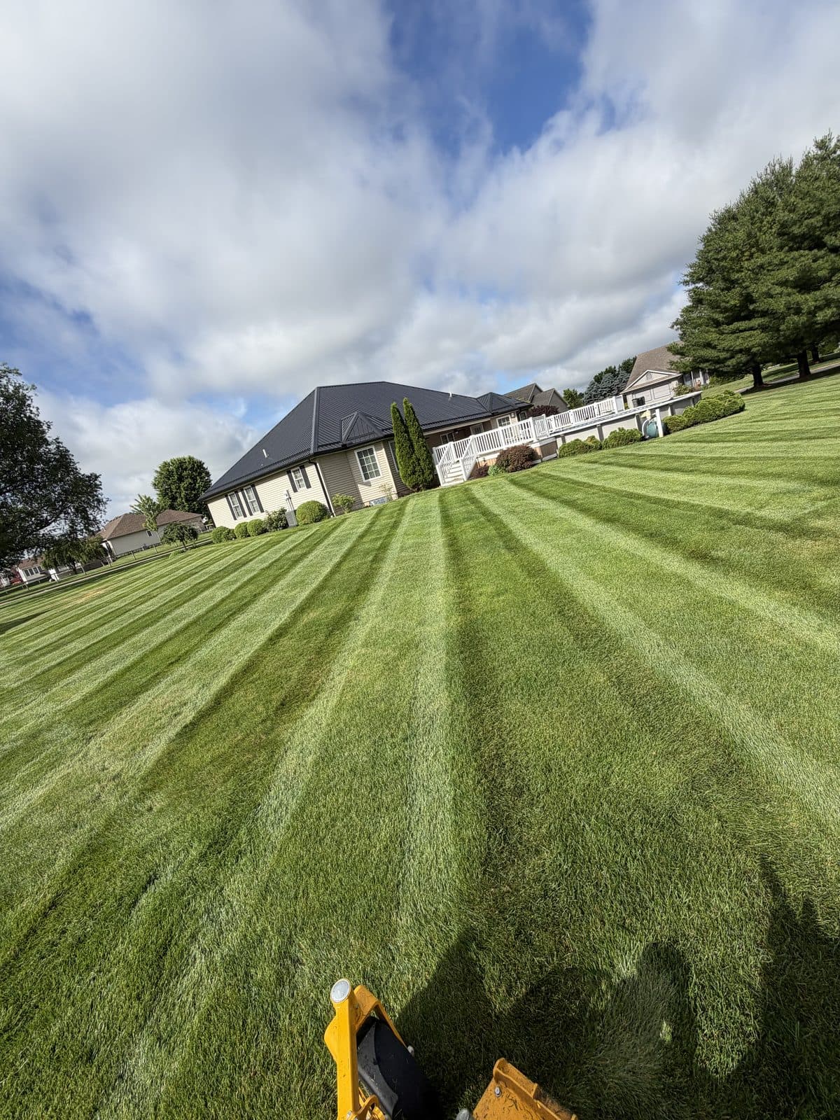 A Fresh Cut Lawns zero-turn mower cutting stripes across a large green lawn