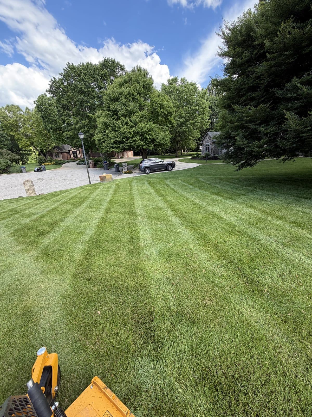 A Fresh Cut Lawns zero-turn mower cutting crisp green stripes across a lawn.